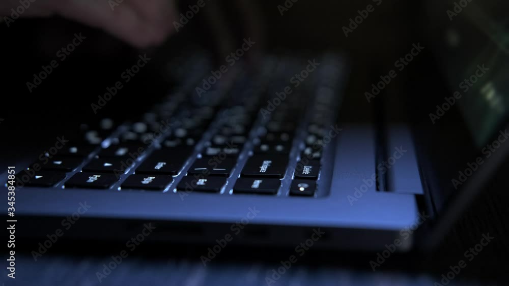 Hacker typing on laptop keyboard. Close-up of hands stroking keys. Flashlights are reflected on keyboard. Cybercrime concept in 4K, UHD Hacker typing on laptop keyboard. Close-up of hands stroking keys. Flashlights are reflected on keyboard. Cybercrime concept in 4K, UHD