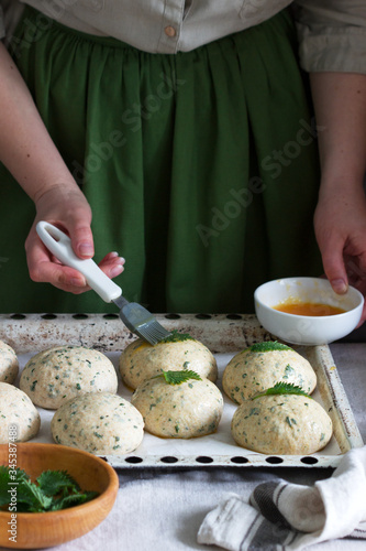 Obraz na płótnie A woman is preparing buns from yeast dough with nettles. Rustic style. w salonie