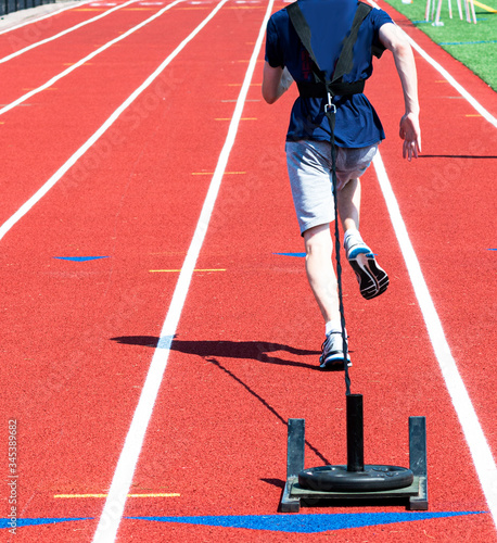 Runner pulling wighted sled on a track from behind