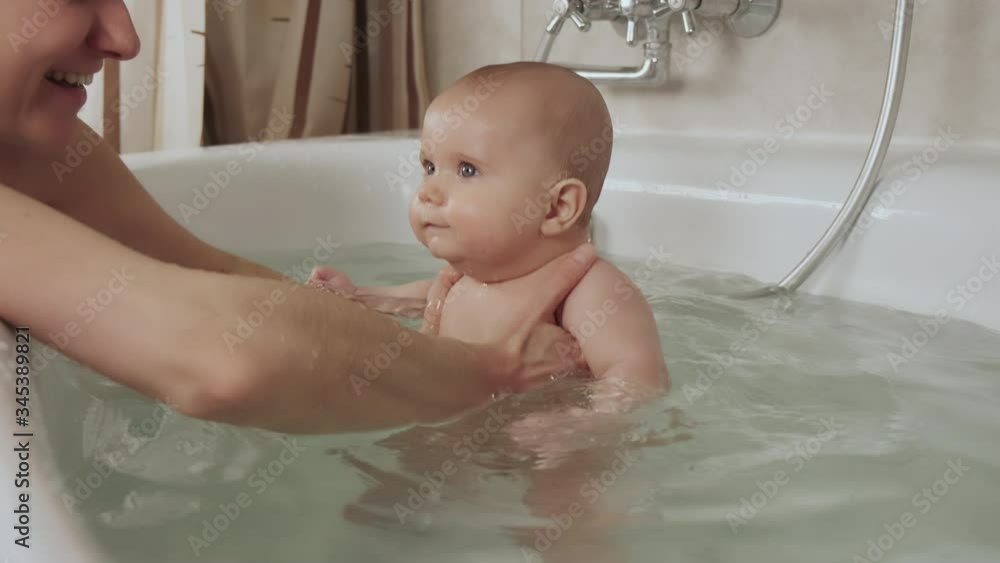 Hands of a careful unknown mother hold a small beautiful funny big-eyed baby. The concept of care and hygiene over children. 4K UHD still video camera, 2x slow motion. Hands of a careful unknown mother hold a small beautiful funny big-eyed baby. The concept of care and hygiene over children. 4K UHD still video camera, 2x slow motion.