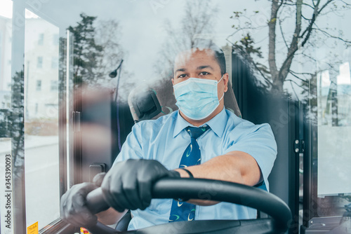 young latin man bus driver in blue shirt has blue medical protection mask and black  gloves on hands. photo