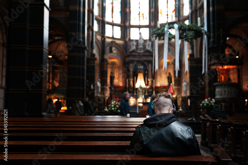 Young man in black leather jacket and headphones sitting in the cathedral bench