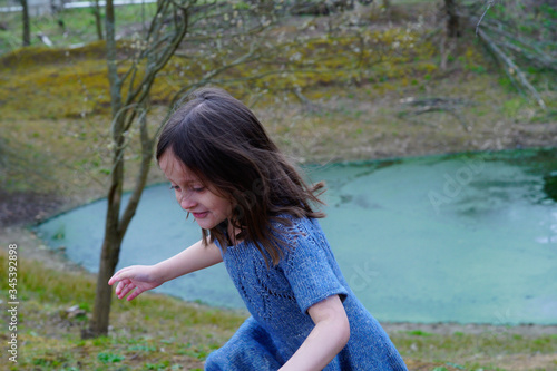 
Little girl in a woolen dress near a small lake in spring