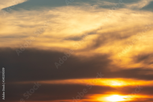 white and gray clouds are illuminated by the bright light of the setting sun. The sun is already on the horizon. Sunset or sunrise over the forest