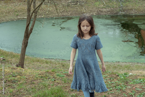 
Little girl in a woolen dress near a small lake in spring