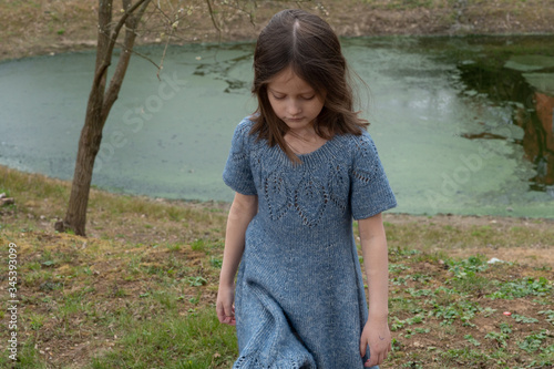 
Little girl in a woolen dress near a small lake in spring