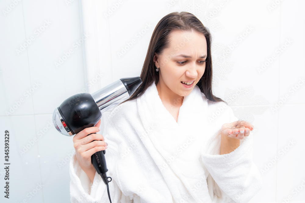 Young woman in bathroom with hairdryer. Hair loss in women. Girl with problem hair. Excessive hair. Alopecia. Young woman in bathroom with hairdryer. Hair loss in women. Girl with problem hair. Excessive hair. Alopecia.