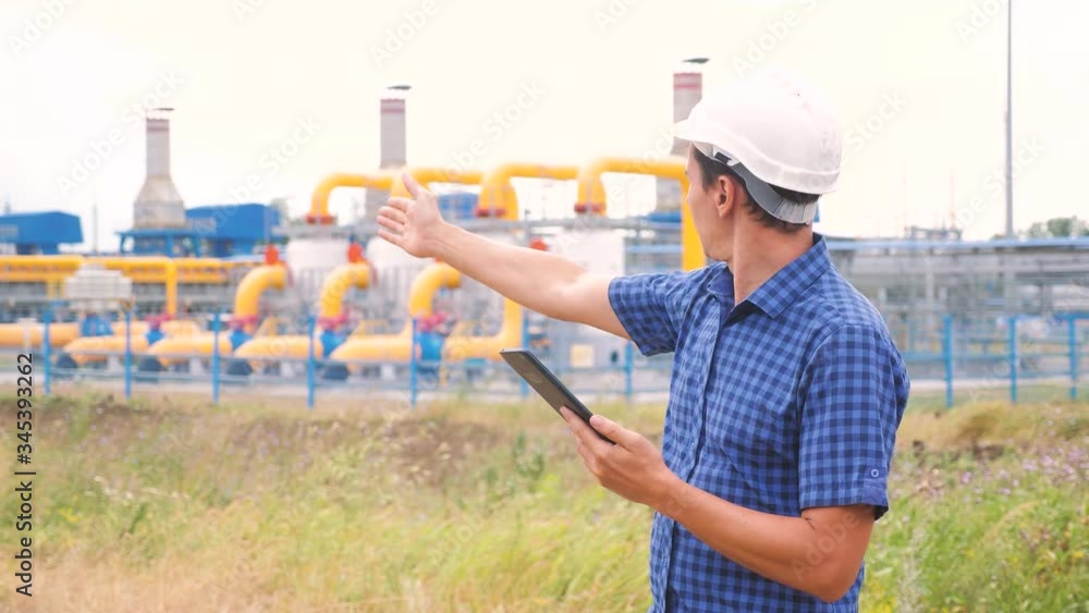 mining oil gas production industry concept. engineer man power and energy using digital tablet. lifestyle worker a in helmet works at an oil gas plant. engineer a studies documents business industry mining oil gas production industry concept. engineer man power and energy using digital tablet. lifestyle worker a in helmet works at an oil gas plant. engineer a studies documents business industry