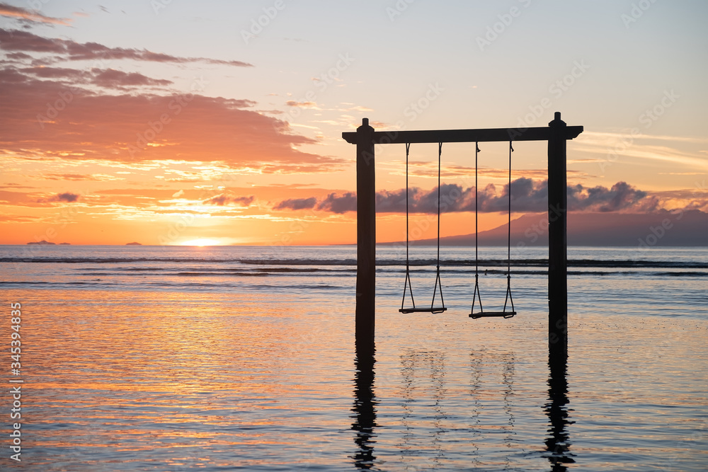 Swing on seashore during the sunrise. Sky and reflections on the water in the summer. Sun rays during the sunrise. Nusa Penida, Bali, Indonesia. Travel - image Swing on seashore during the sunrise. Sky and reflections on the water in the summer. Sun rays during the sunrise. Nusa Penida, Bali, Indonesia. Travel - image