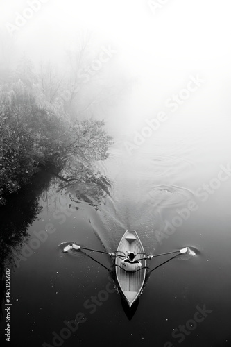 Man in boat in fog. Misty river. Black white photo. Autumn landscape