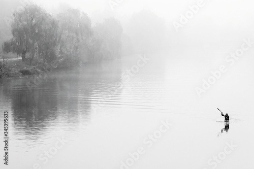 Man on kayak in fog. Misty river. Black white autumn landscape