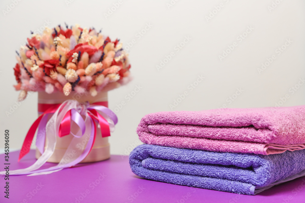 folded towels and dry flower composition on purple table folded towels and dry flower composition on purple table