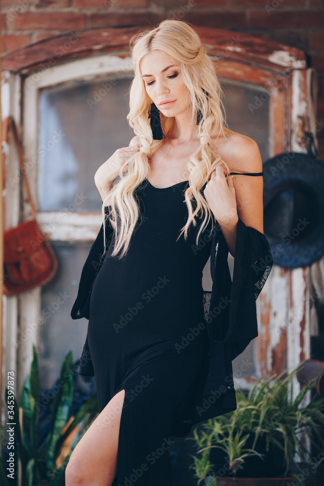 Obraz premium Portrait of beautiful young blonde in the black clothing of style of бохо in a summer arbour