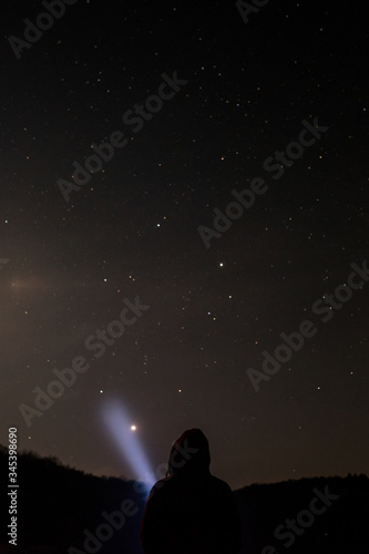 Man shining a flashlight in the starry sky
