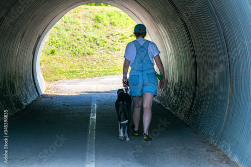 Woman and greyhound walking in tunnel