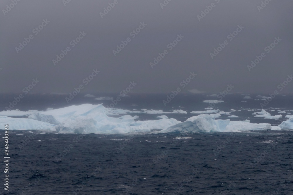 Icebergs in antarctic sea during storm, with dark ocean, Antarctica