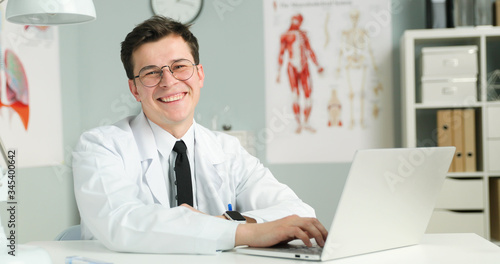 Portrait of young doctor sitting with laptop in medical office