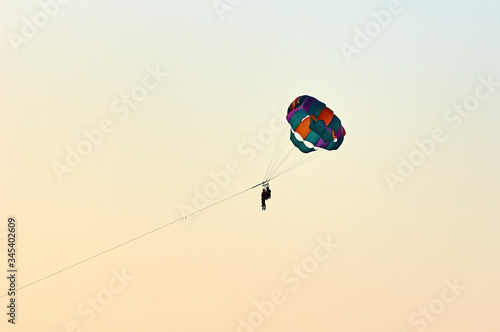 Silhouette of a Parasailers Flying On Colorful Parachute In colorful romantic sunset
