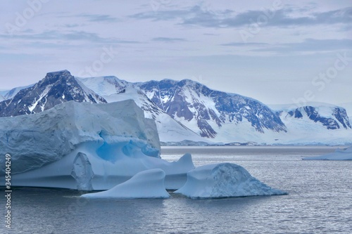 Iceberg with blue ice in antarctic ocean with mountain, stormy sky, Antarctica