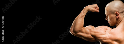 Close-up of a power fitness man's hand. Muscular bodybuilder flexing and showing his biceps - external side - on black background. Studio shot