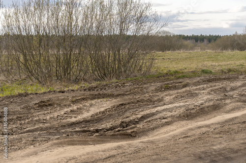 dirt damaged rural spring road in a field. concept of problem with the roads