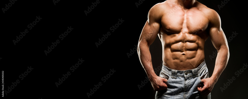 Portrait of strong healthy power fitness handsome athletic man with muscular trained body on black background. Male torso in blue jeans. Strength and motivation