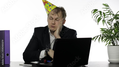 Drank sleepy young businessman with hangover in festive cap falling asleep photo