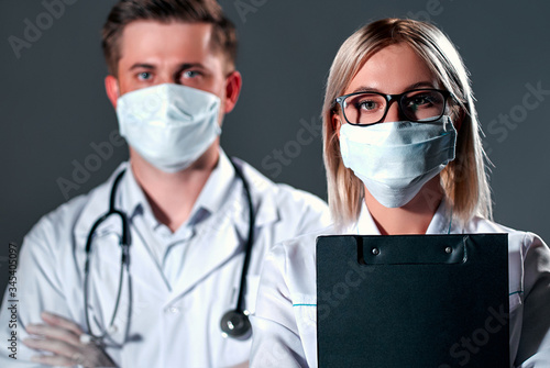 Two doctors in protective masks and gloves isolated on a dark gray background. Coronavirus concept.