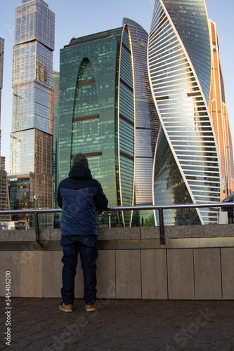 Young man standing looking on Modern skyscrapers in business district in evening light at sunset