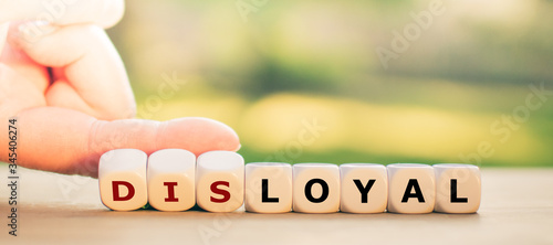 Hand turns dice and changes the expression "disloyal" to "loyal".