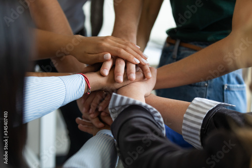 Close up multiracial business people putting hands together  showing support and unity. Diverse colleagues joining in team building activity  staff training concept  start working together  teamwork.