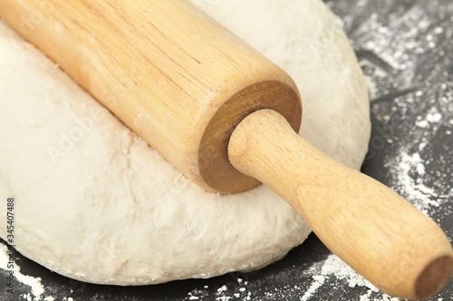 Dough and wood rolling pin on clean black background Close up
