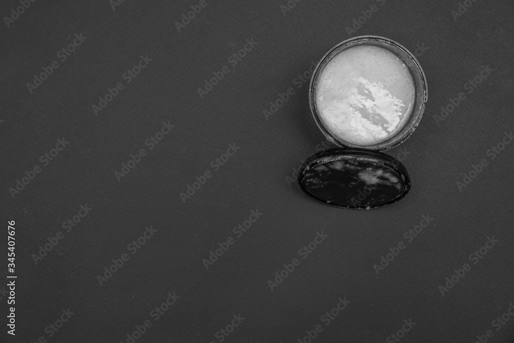Scrub in a black jar on a black background. Home care for body and face. Quarantine. Space for text. Scrub in a black jar on a black background. Home care for body and face. Quarantine. Space for text.