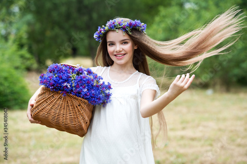 Beautiful girl in a wreath of the cornflowers and with a bouquet in basket. Ivana Kupala