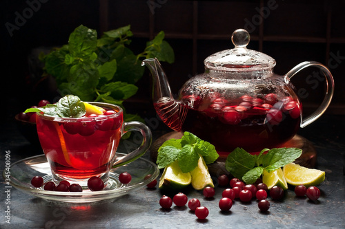 Glass cup and teapot of hot tea with mint and berry