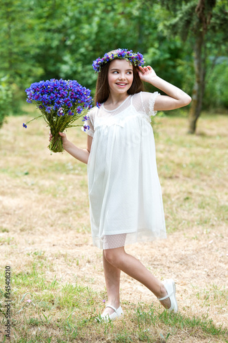 Beautiful girl in a wreath of the cornflowers and with a bouquet in basket. Ivana Kupala