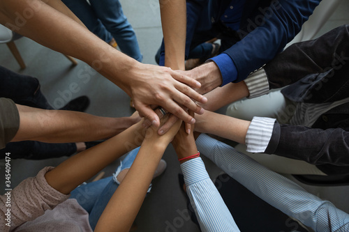 Close up mixed race business people putting hands together  support and unity concept. Diverse colleagues joining in team building activity  staff training concept  start working together  teamwork.