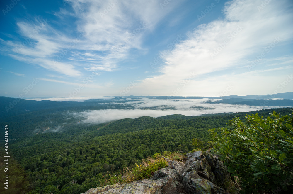 view of the valley from the height of the mountain range in fog view of the valley from the height of the mountain range in fog