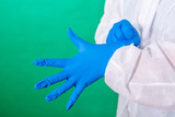 COVID-19. Facial masks on the pile. Epidemic background. Close up of female doctor's hands putting on blue sterilized surgical gloves in the office.