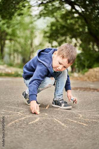 funny boy draws the sun on the asphalt