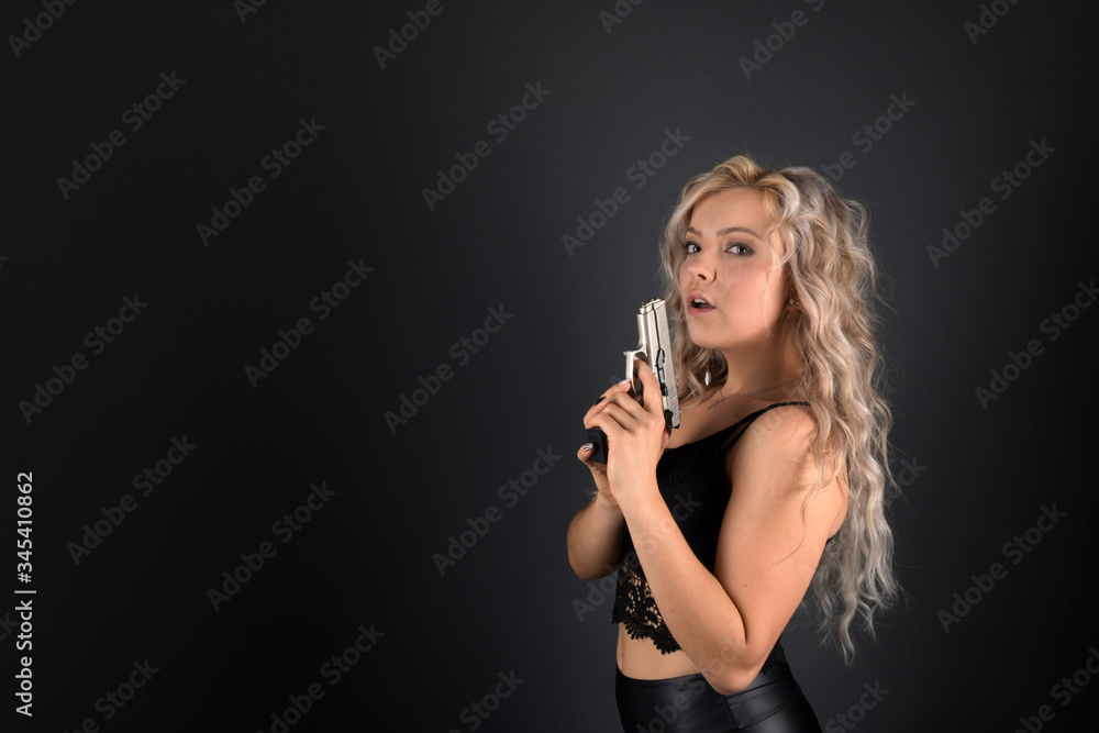 Plakat A beautiful blonde model holds a pistol for protection