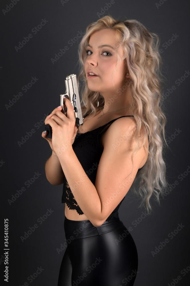 A beautiful blonde model holds a pistol for protection A beautiful blonde model holds a pistol for protection