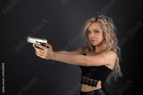 A beautiful blonde model holds a pistol for protection
