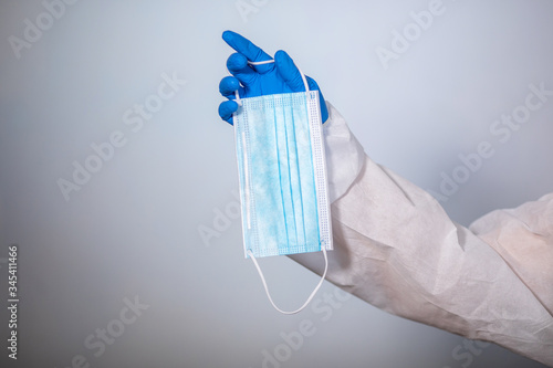 COVID-19. Facial masks on the pile. Epidemic background. Close-up. A medical worker in a protective anti-plague suit holds a maditsin mask with rubber disposable gloves photo