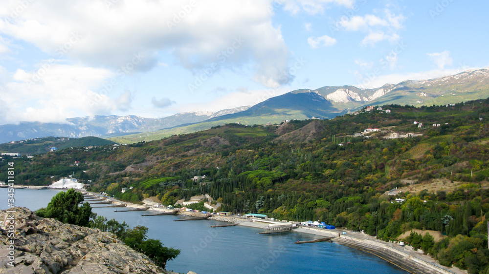 panoramic view from the heights of the forested coast of sea, mountains and blue sky with clouds