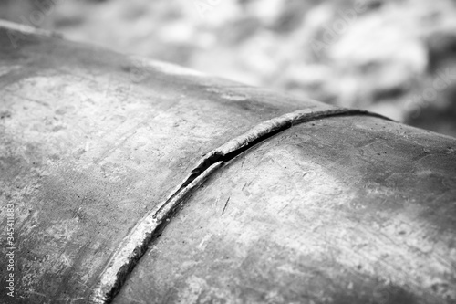 A fragment of the main pipeline for pumping gas. In the frame, the weld defect is a hole and a crack on the steel pipe. Black and white image. photo