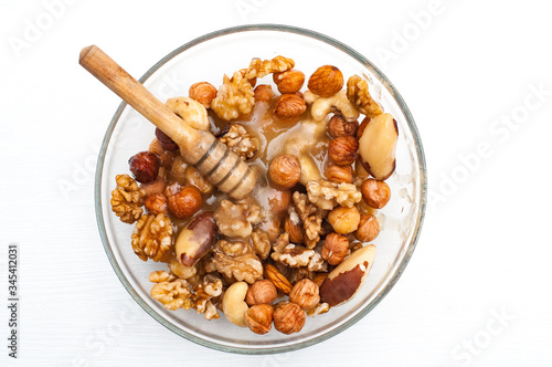 Mixed nuts with honey . Brazil nuts, walnuts and hazelnuts on white wooden background. Healthy food concept. Vegetarian food. Raw food concept