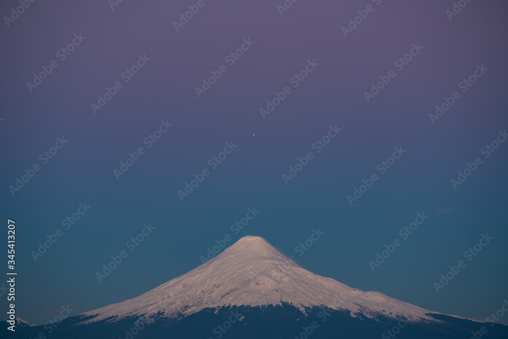 planet Jupiter aligned with the top of the Osorno volcano during the blue hour after sunset