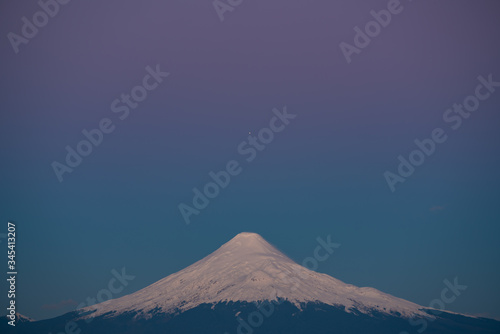 planet Jupiter aligned with the top of the Osorno volcano during the blue hour after sunset