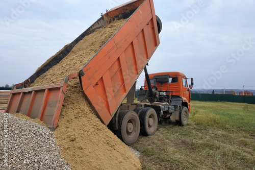 Fototapeta A dump truck unloads sand at a construction site.